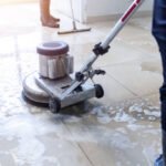 Janitor use floor scrubber machine on the floor hallway office building or walkway after school and classroom work job with sun light background. Wet floor or cleaning service house maid concept.