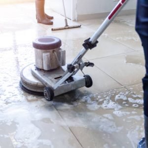 Janitor use floor scrubber machine on the floor hallway office building or walkway after school and classroom work job with sun light background. Wet floor or cleaning service house maid concept.